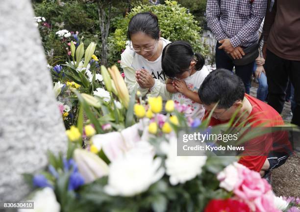 People pray in front of a cenotaph on Osutaka Ridge, atop a mountain in Gunma Prefecture, northwest of Tokyo, on Aug. 12 the 32nd anniversary of the...