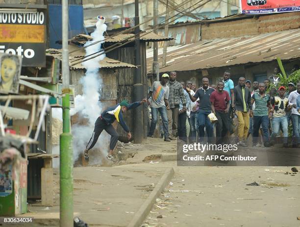 Protester throws a tear gas canister back during confrontations between Kenyan security forces and supporters of opposition coalition National Super...