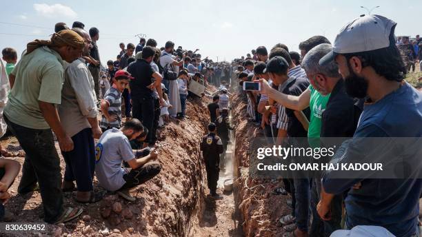 Members of the Syrian civil defence volunteers, also known as the White Helmets, bury their fellow comrades during a funeral in Sarmin, a...