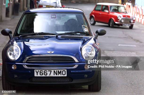 The new Williams BMW Mini passes its distant relative as it drives around the streets of Manchester during the national launch for dealers of the...