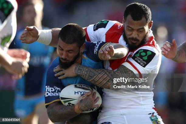 Nathan Peats of the Titans is tackled by Leeson Ah Mau of the Dragons during the round 23 NRL match between the St George Illawarra Dragons and the...