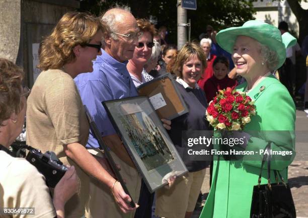 Britain's Queen Elizabeth II is shown images of her last visit to Alderney, in 1989, by Mr Ian Waterfall on the island of Alderney, on the first day...