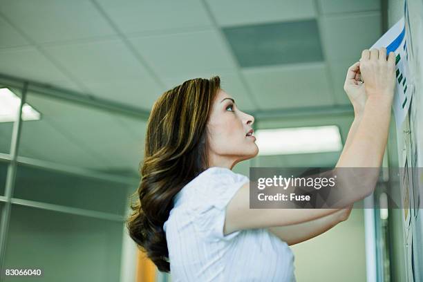 woman posting flyer on bulletin board - bulletin board flyer stock pictures, royalty-free photos & images