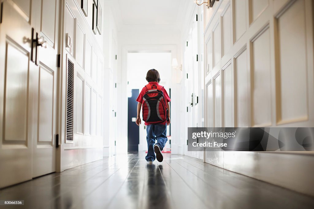 Boy Walking in Hallway Wearing Backpack