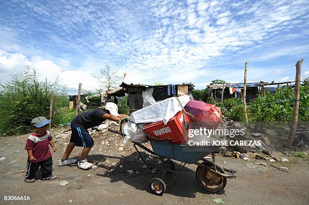 Edwin Elias Campos walks next to his brother Ronald Rolin Ayala of 10, as he pushes a cart full of plastic bottles to sell in La Bendicion de Dios...