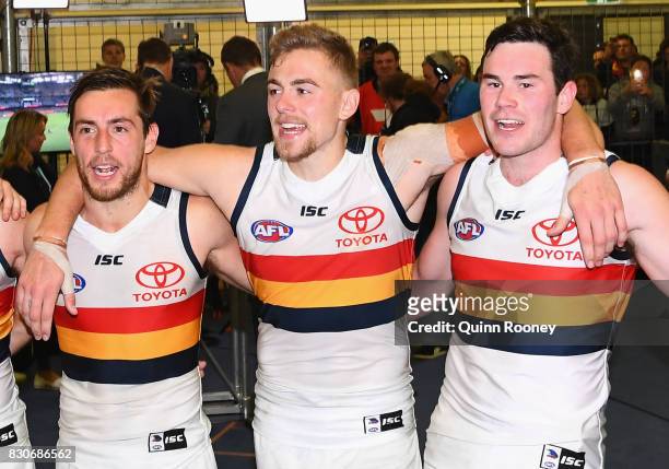 Richard Douglas, Hugh Greenwood and Mitchell McGovern of the Crows sing the song in the rooms after winning the round 21 AFL match between the...