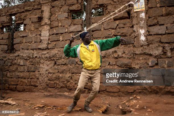 An opposition supporter prepares a slingshot to use against Kenyan police forces as the two sides clashed in the Kibera slum on August 12, 2017 in...
