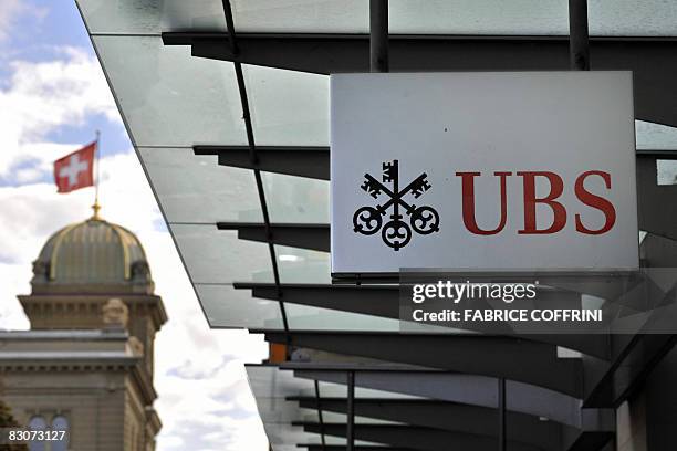 The logo of UBS is displayed on a branch of the Swiss bank with the house of the Swiss Parliament as background on October 1, 2008 in Bern. Shares in...