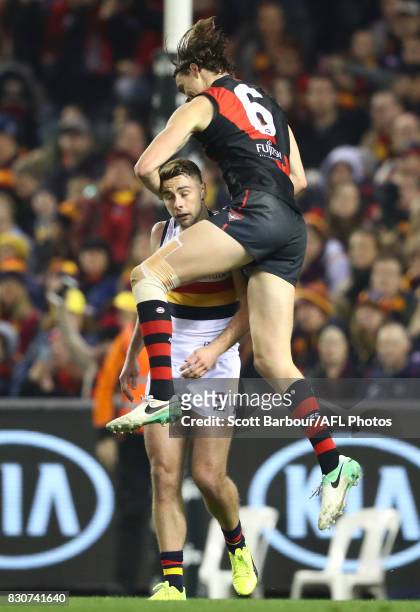 Joe Daniher of the Bombers jumps on Rory Atkins of the Crows as he celebrates after kicking a goal during the round 21 AFL match between the Essendon...
