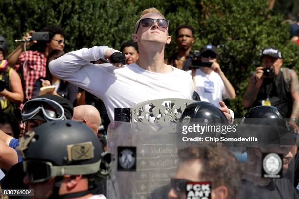 Man makes a slashing motion across his throat twoard counter-protesters as he marches with other white nationalists, neo-Nazis and members of the...