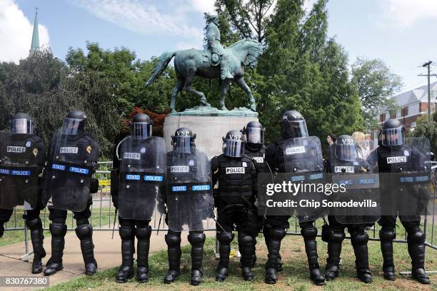 Virginia State Police in riot gear stand in front of the statue of General Robert E. Lee before forcing white nationalists, neo-Nazis and members of...