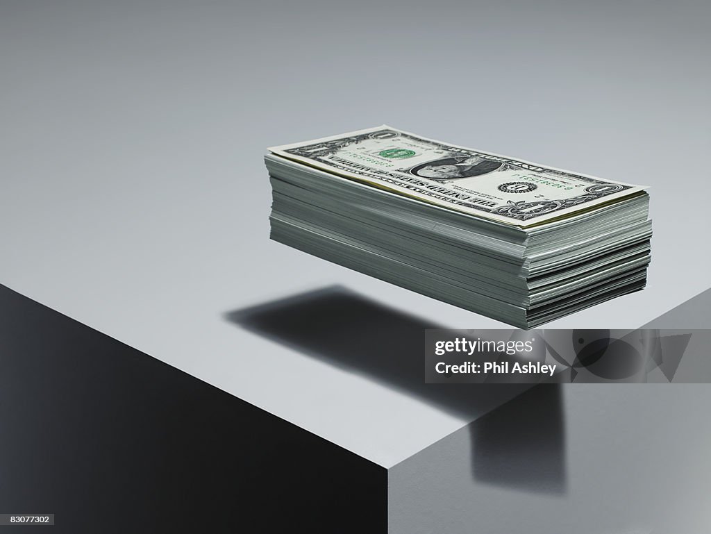 Pile of dollar bills levitating above surface