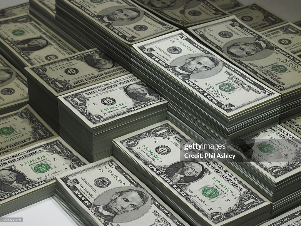 Piles of dollar bills reflected in glass