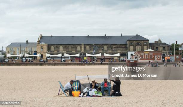 Beachgoers sit on the main beach on August 12, 2017 in Great Yarmouth, England. A cloudy overcast day greeted visitors to the Norfolk seaside town on...