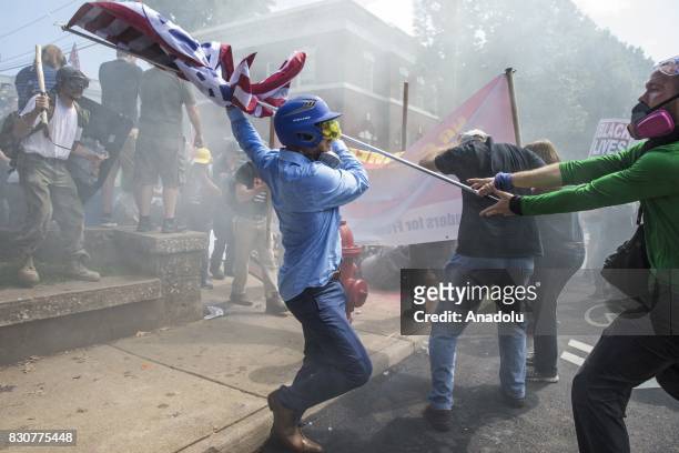 August 12: A White Supremacist tries to strike a counter protestor with a White Nationalist flag during clashes at Emancipation Park where the White...