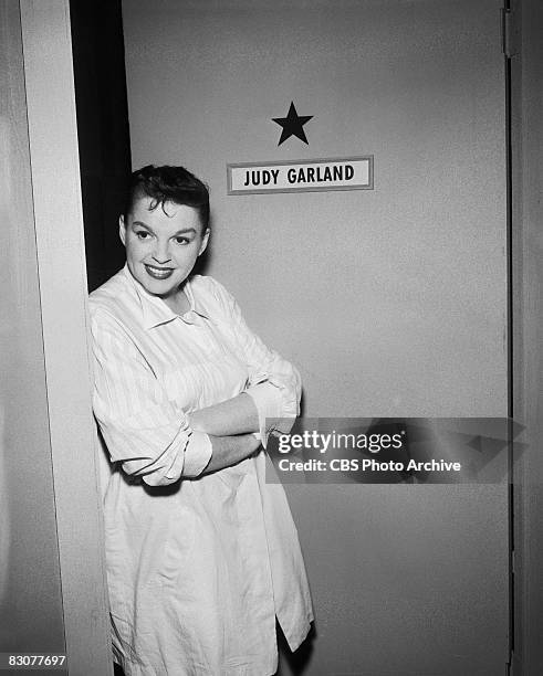 American actress and singer Judy Garland stands outside her dressing room door backstage on the set of the live performance anthology series 'Ford...