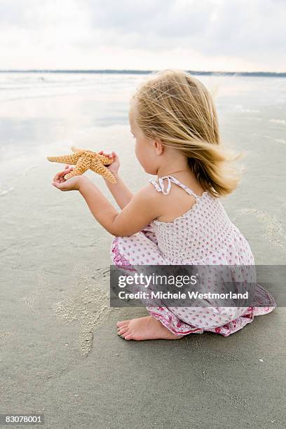 young girl finds starfish on beach - hilton head photos et images de collection