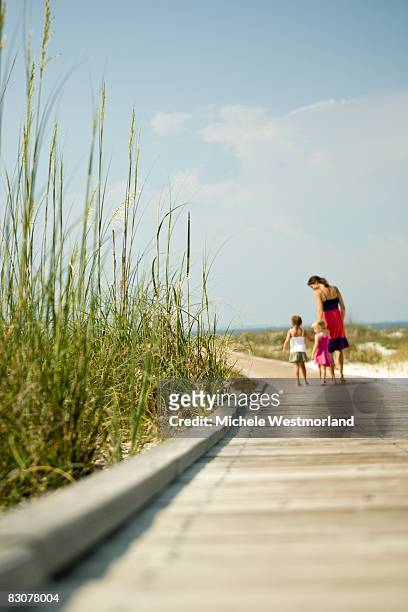 mother with daughters strolling on beach boardwalk - hilton head stock pictures, royalty-free photos & images