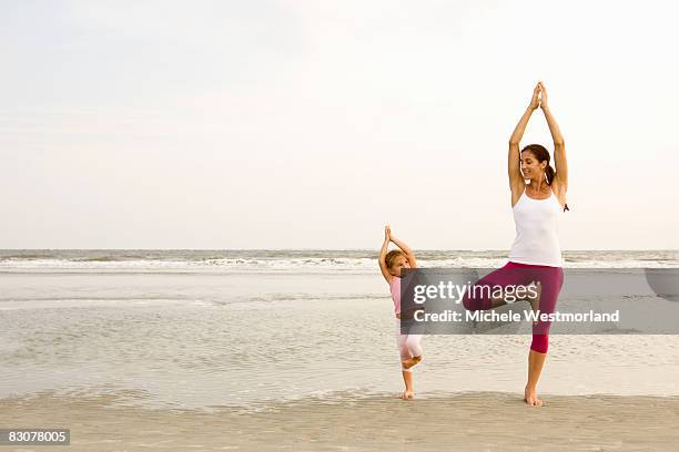 mother teaches daughter yoga on beach - family yoga photos et images de collection