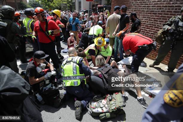 Rescue workers and medics tend to many people who were injured when a car plowed through a crowd of anti-facist counter-demonstrators marching...