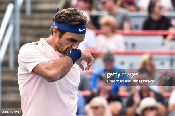 Roger Federer of Switzerland wipes his face against Robin Haase of Netherlands during day nine of the Rogers Cup presented by National Bank at...