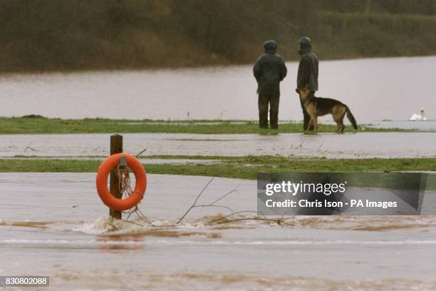 Dog walkers wander through fields beside the River Usk which burst its banks in Abergavenny, Wales. The Environment Agency Wales confirmed three...