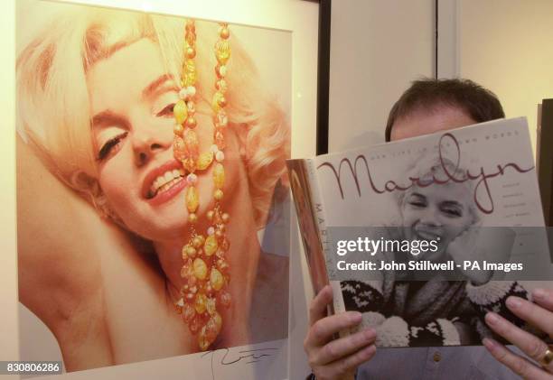 Prospective buyer studies a picture book of film-star Marilyn Monroe, next to a picture that was taken in 1962, six weeks before her death and is...
