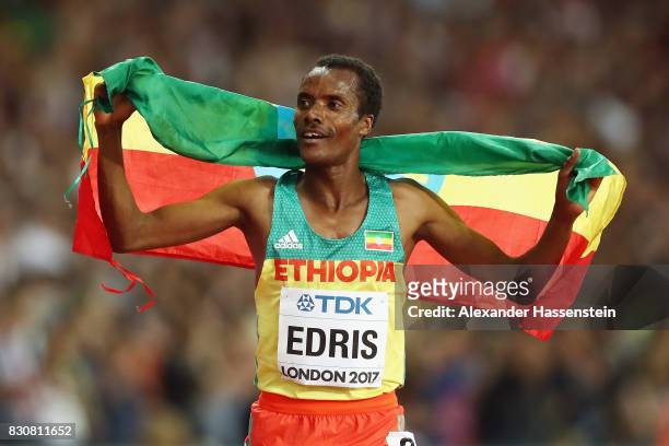 Muktar Edris of Ethiopia celebrates with the Ethiopian flag after winning gold in the Men's 5000 Metres final during day nine of the 16th IAAF World...