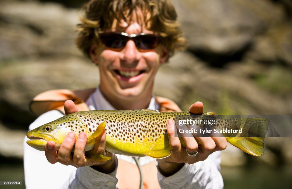 Photo of man smiling and holding a Rainbow Trout