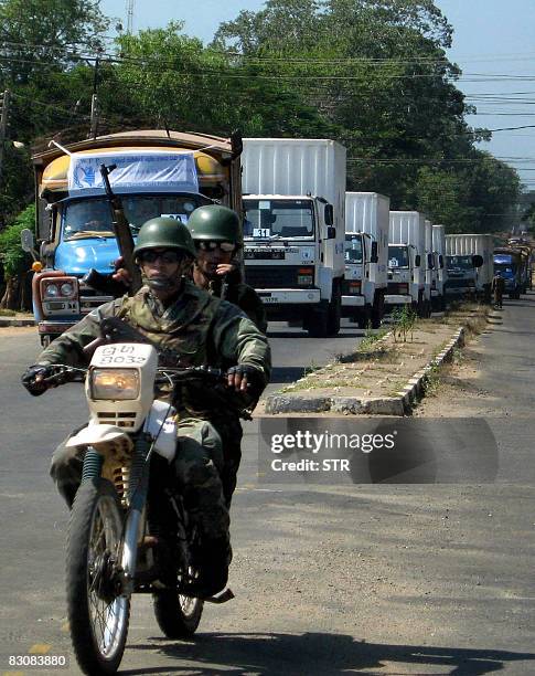 Sri Lankan soldiers ride on a motorcycle as they escort a convoy of food supplies as it leaves Vavuniya, some 200kms north of Colombo on October 2...