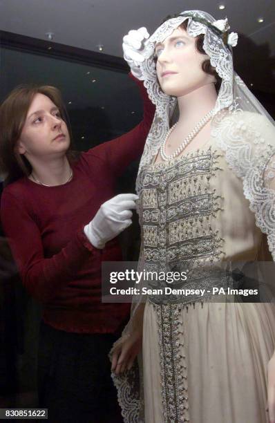 Curator, Jenny Lister puts on the finishing touches to the Queen Elizabeth The Queen Mother wedding dress at Kensington Palace. A century of wedding...