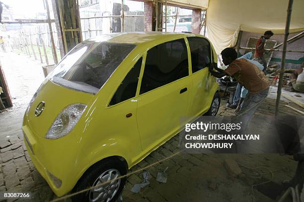 An Indian worker touches up a replica of a Tata Nano automobile at place of worship for the upcoming Durga Puja festival in Kolkata on October 2,...