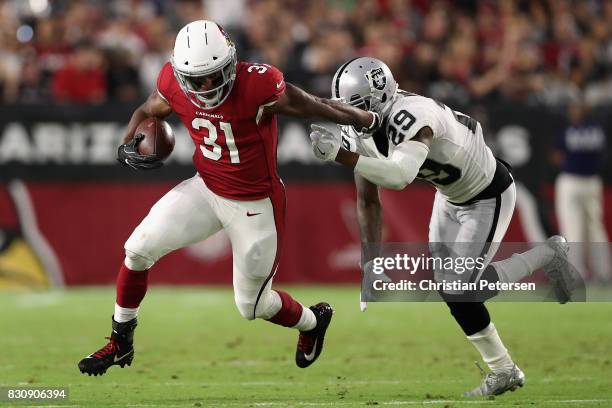 Running back David Johnson of the Arizona Cardinals rushes the football past cornerback David Amerson of the Oakland Raiders during the first half of...