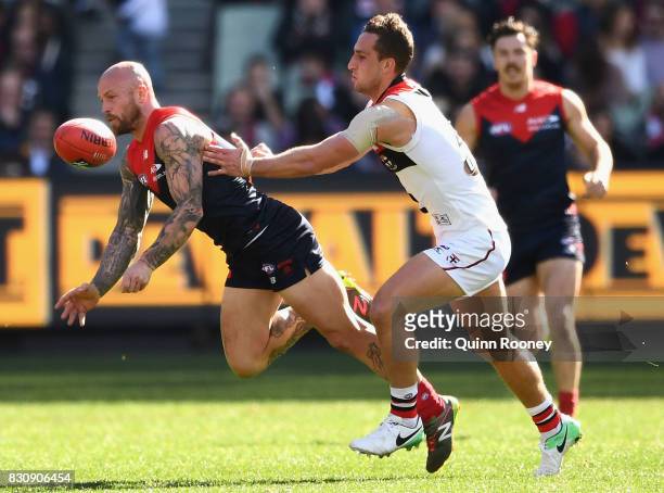 Nathan Jones of the Demons handballs whilst being tackled by Luke Dunstan of the Saints during the round 21 AFL match between the Melbourne Demons...