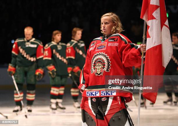 Minor league hockey player holds the Canadian flag during the playing of the national anthems before a game between the Ottawa Senators and the...