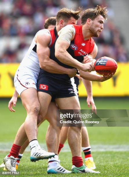 Jack Viney of the Demons handballs whilst being tackled by Maverick Weller of the Saints during the round 21 AFL match between the Melbourne Demons...