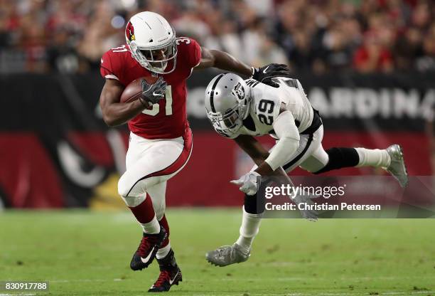 Running back David Johnson of the Arizona Cardinals rushes the football past cornerback David Amerson of the Oakland Raiders during the first half of...