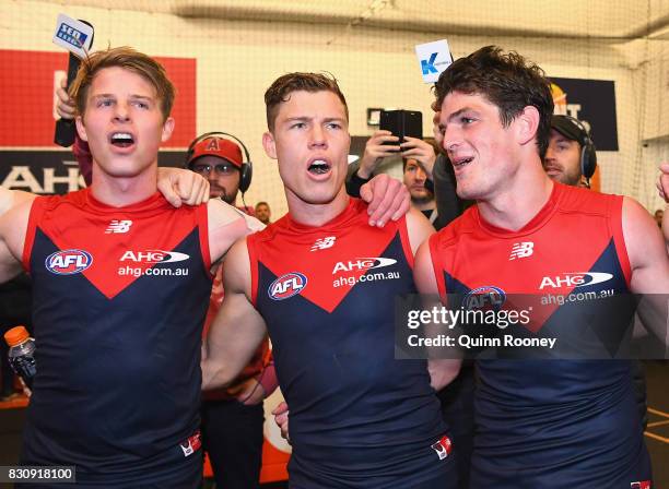 Mitch Hannan, Jake Melksham and Angus Brayshaw of the Demons sing the song in the rooms after winning the round 21 AFL match between the Melbourne...