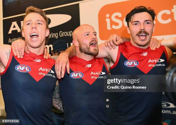 James Harmes, Nathan Jones and Michael Hibberd of the Demons sing the song in the rooms after winning the round 21 AFL match between the Melbourne...