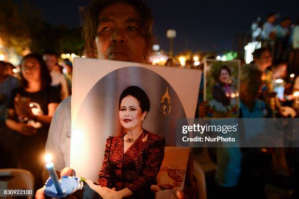 Thai people hold up pictures Thai Queens Sirikit and lights candle his celebrate of Queens Sirikit birthday in Bangkok, Thailand, 12 August 2017.