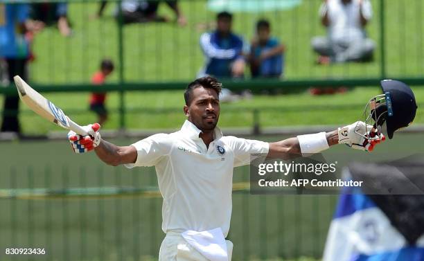 India's Hardik Pandya raises his bat and helmet in celebration after scoring a century during the second day of the third and final Test match...