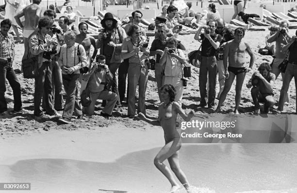 An aspiring starlet causes a reaction among the beach paparazzi gathered at the 1980 Cannes, France, Film Festival as she runs on the beach.