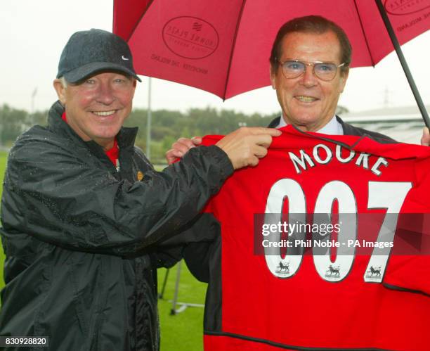 Manchester United manager Sir Alex Ferguson presents former James Bond actor Roger Moore, with a personalised Manchester United strip during the...