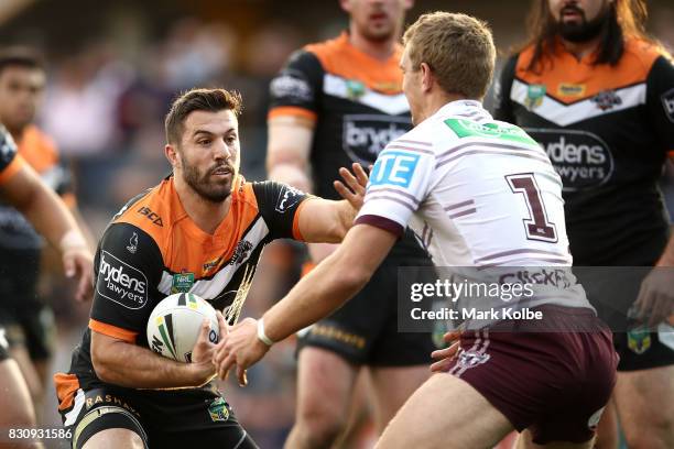 James Tedesco of the Tigers fends away Tom Trbojevic of the Sea Eagles during the round 23 NRL match between the Wests Tigers and the Manly Sea...