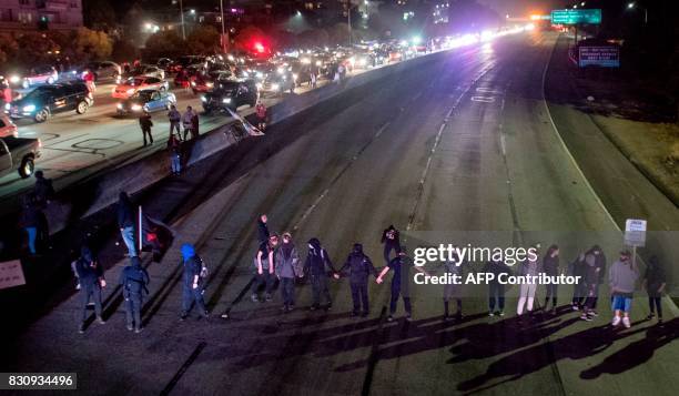 Protesters block both directions of the Interstate 580 freeway during a rally against racism in Oakland, California on August 12, 2017. Protesters...