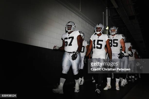 Offensive guard Oni Omoile, wide receiver Michael Crabtree and tight end Ryan O'Malley of the Oakland Raiders lead teamamtes onto the field before...