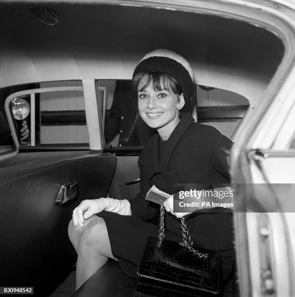 Audrey Hepburn in an attractive two colour contrasting fur hat, after her flight to Heathrow from Rome. She is here to attend the European premiere...