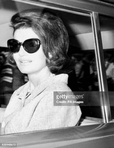 Smile from Mrs Jacqueline Kennedy as, wearing sunglasses, she sets off by car from her sisters home, where she is staying.