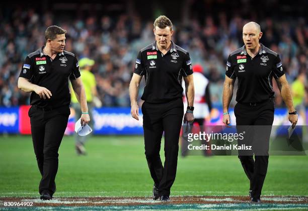 Magpies midfield coach Scott Burns, Magpies head coach Nathan Buckley and Magpies assistant coach Brenton Sanderson walk from the field during the...
