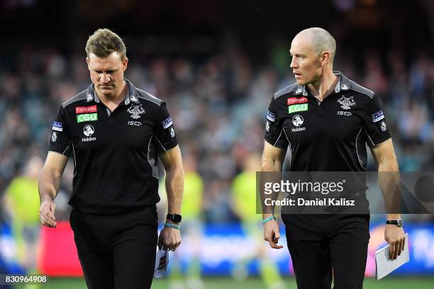 Magpies head coach Nathan Buckley and Magpies assistant coach Brenton Sanderson walk from the field during the round 21 AFL match between Port...